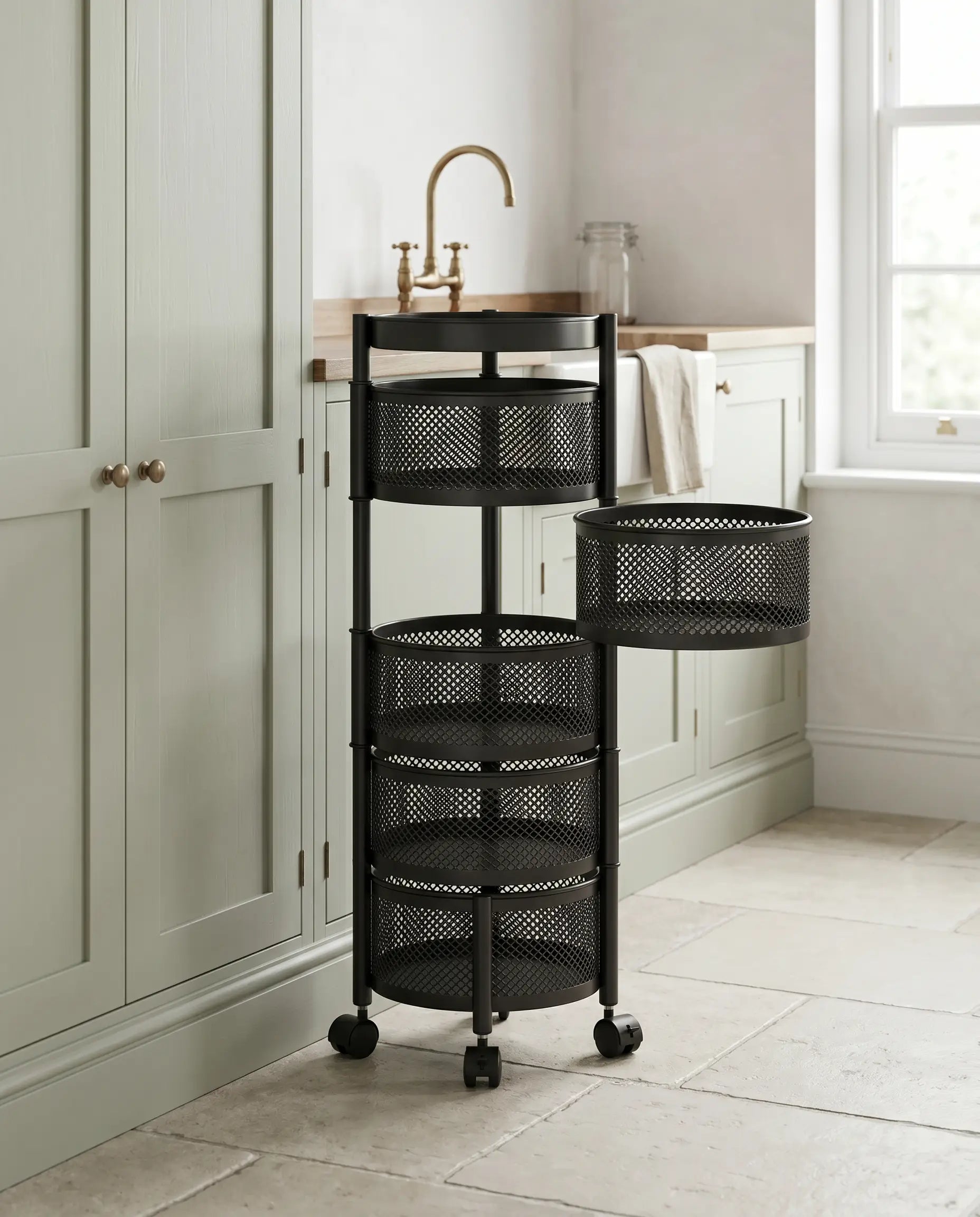 Black round mesh basket trolley beside sage cupboards
